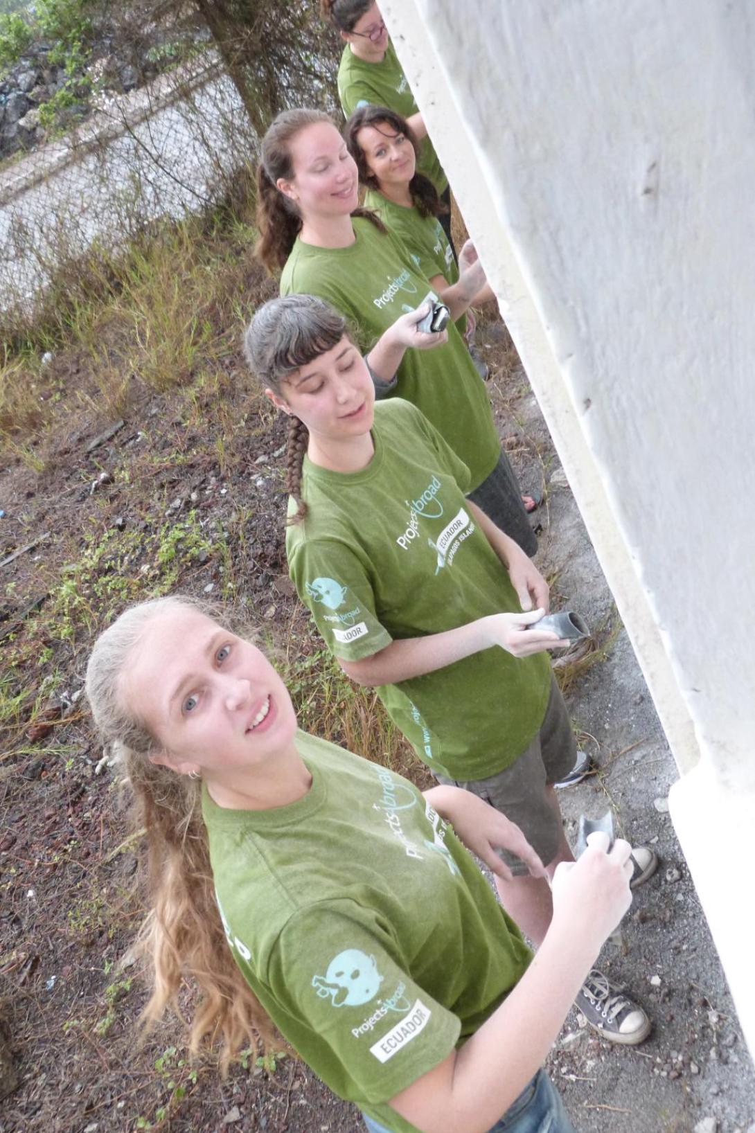Volunteers in Ecuador helping to paint a wall with Projects Abroad Ecuador volunteer group painting a wall